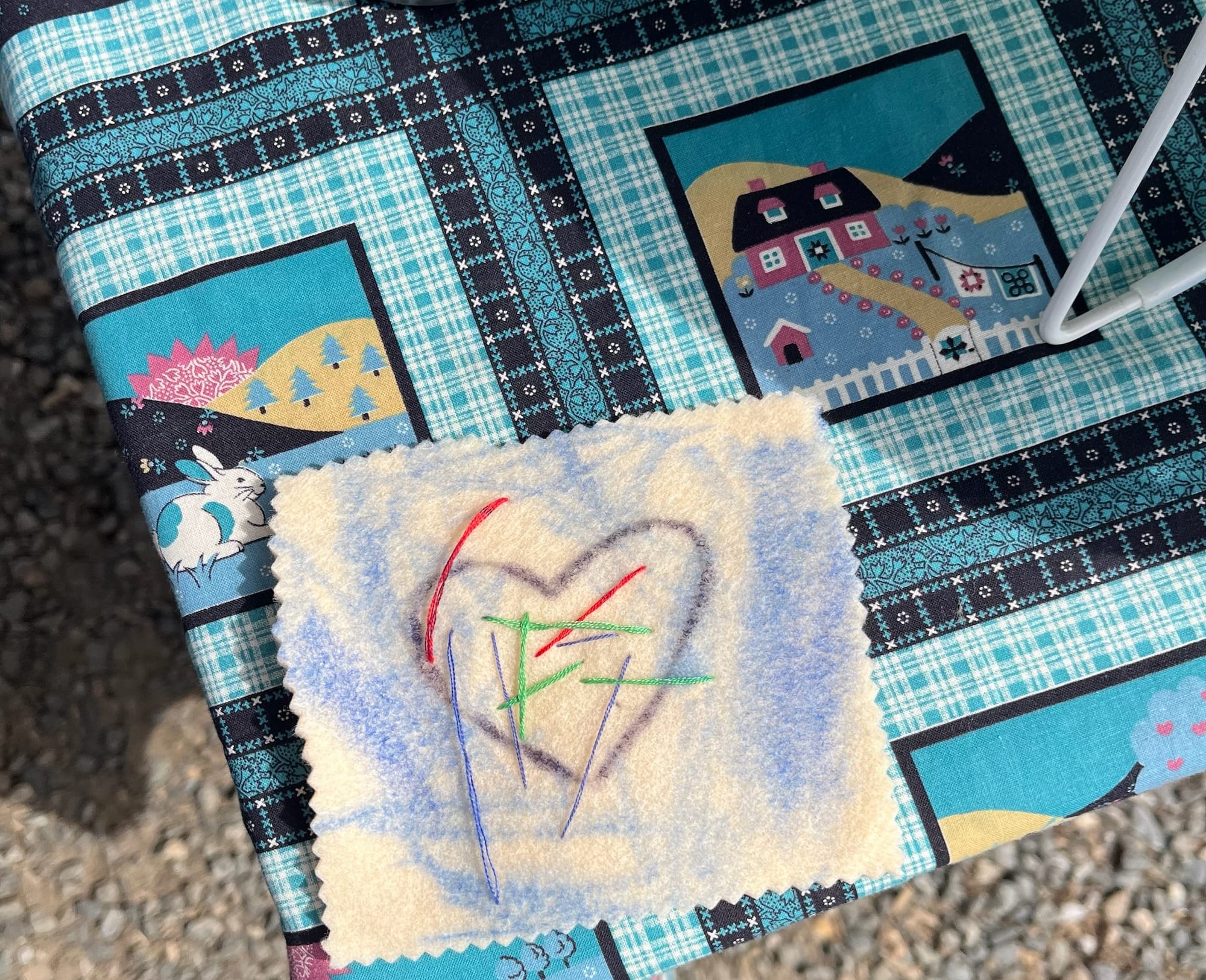 A heart stitched onto a fleece square in three colors of floss