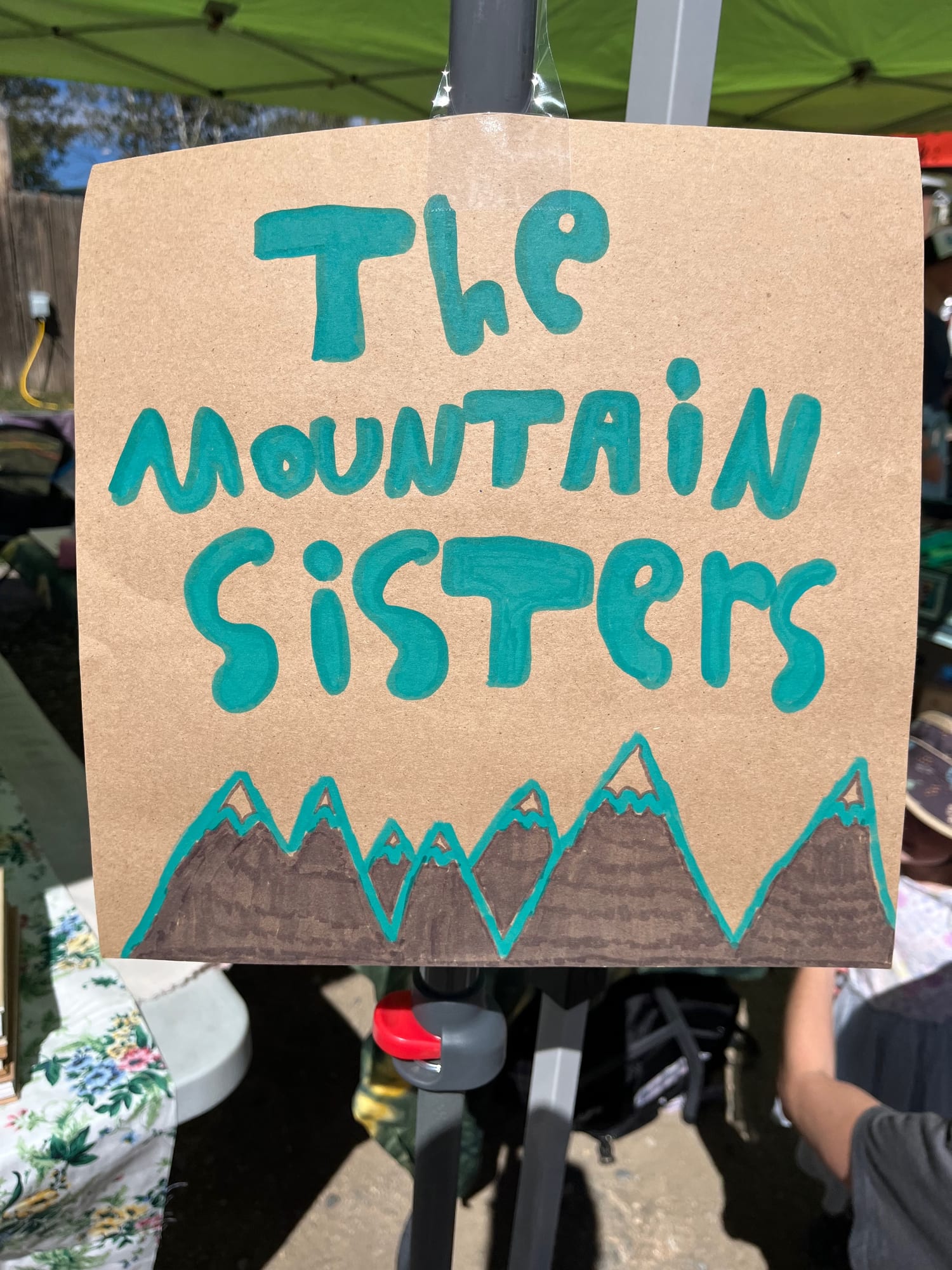 A hand-drawn booth sign for The Mountain Sisters